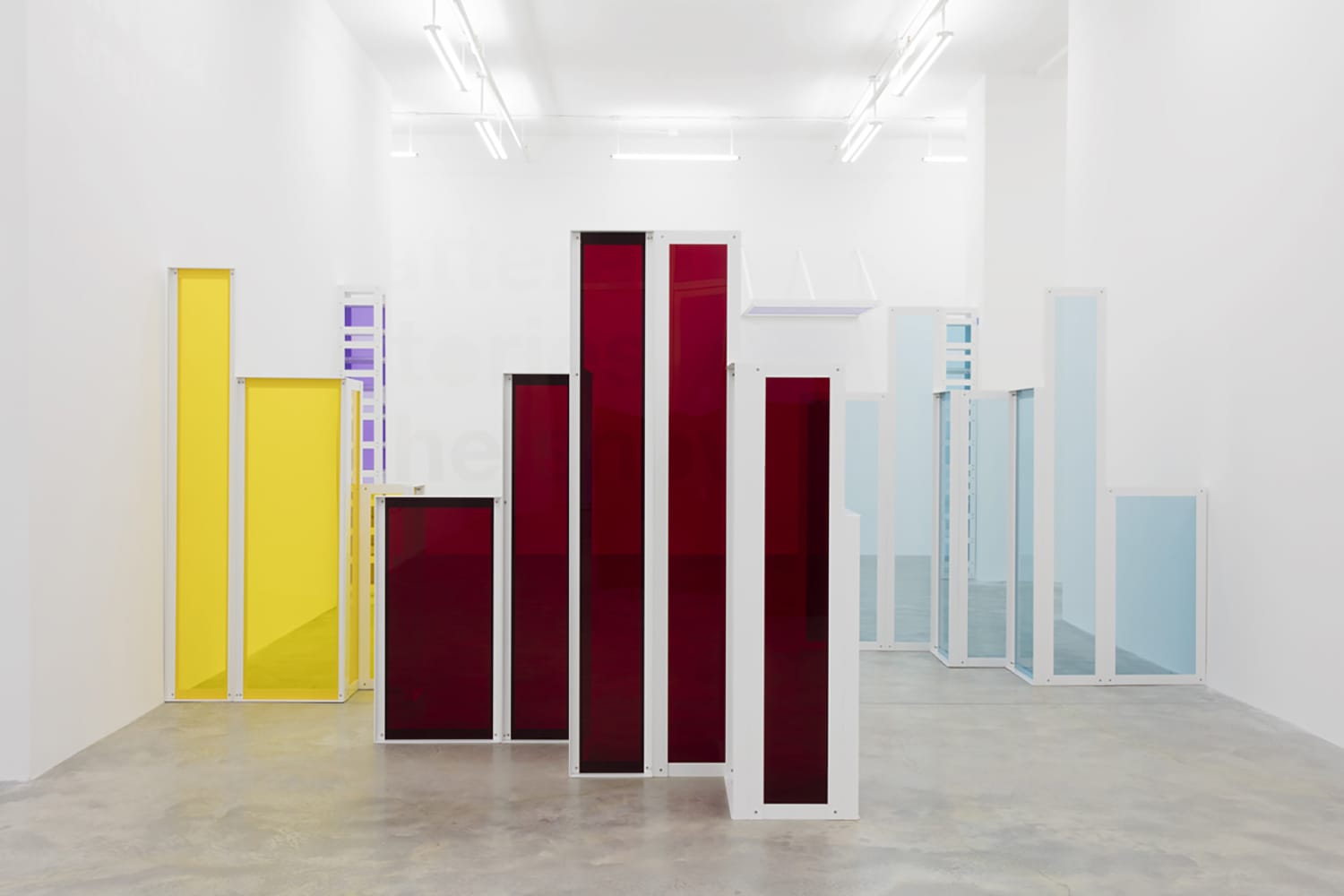 Abstract art installation with colorful vertical panels in a gallery, featuring red, yellow, and blue sections.