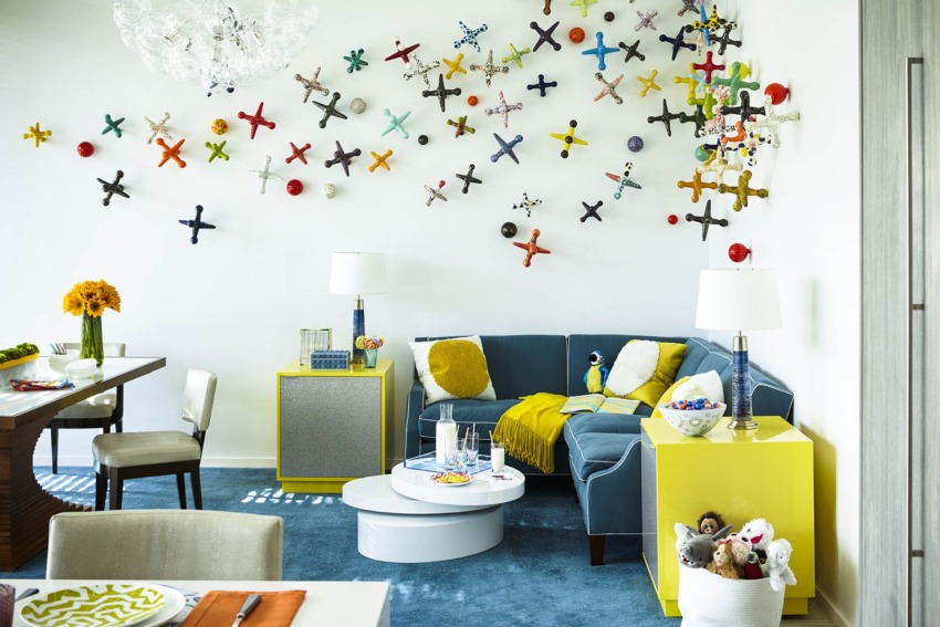 bright modern living room with colorful abstract wall art, blue sectional sofa, yellow accents, and decorative tables