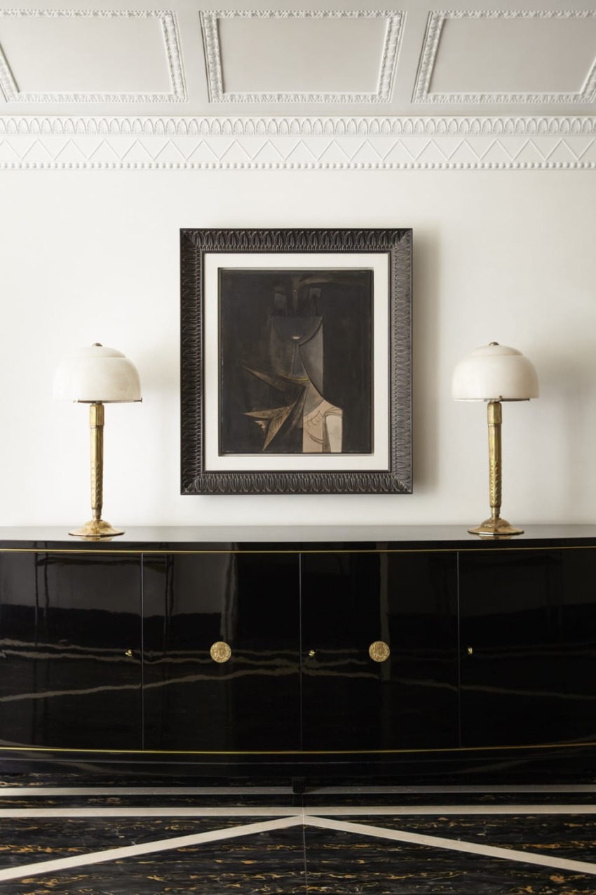 Elegant interior featuring a modern art painting, black console, and two decorative lamps.