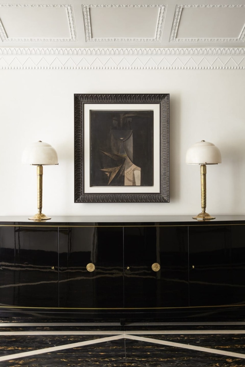 Elegant interior featuring a modern art painting, black console, and two decorative lamps.