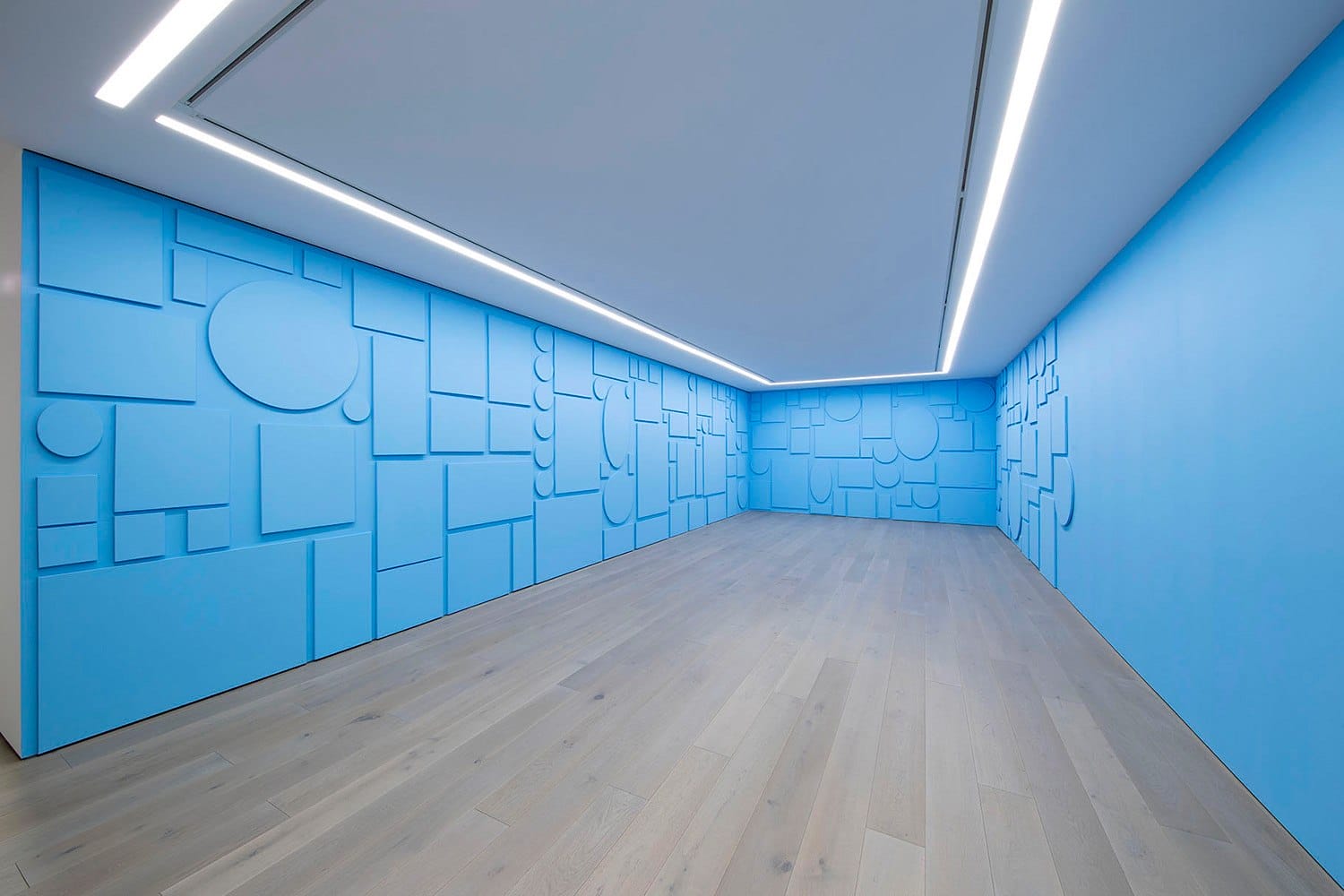 Modern room with blue geometric patterned walls, light wooden floor, and LED ceiling lights.