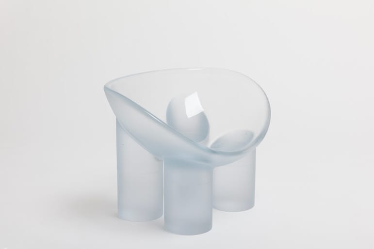 Frosted glass abstract sculpture with smooth curves and cylindrical supports on a white background.