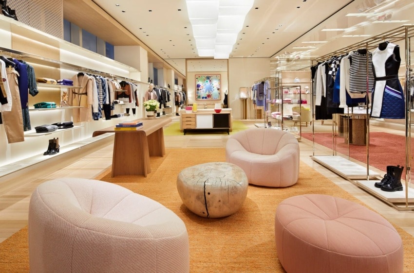 Luxury clothing store interior with modern seating, clothes racks, and stylish decor.