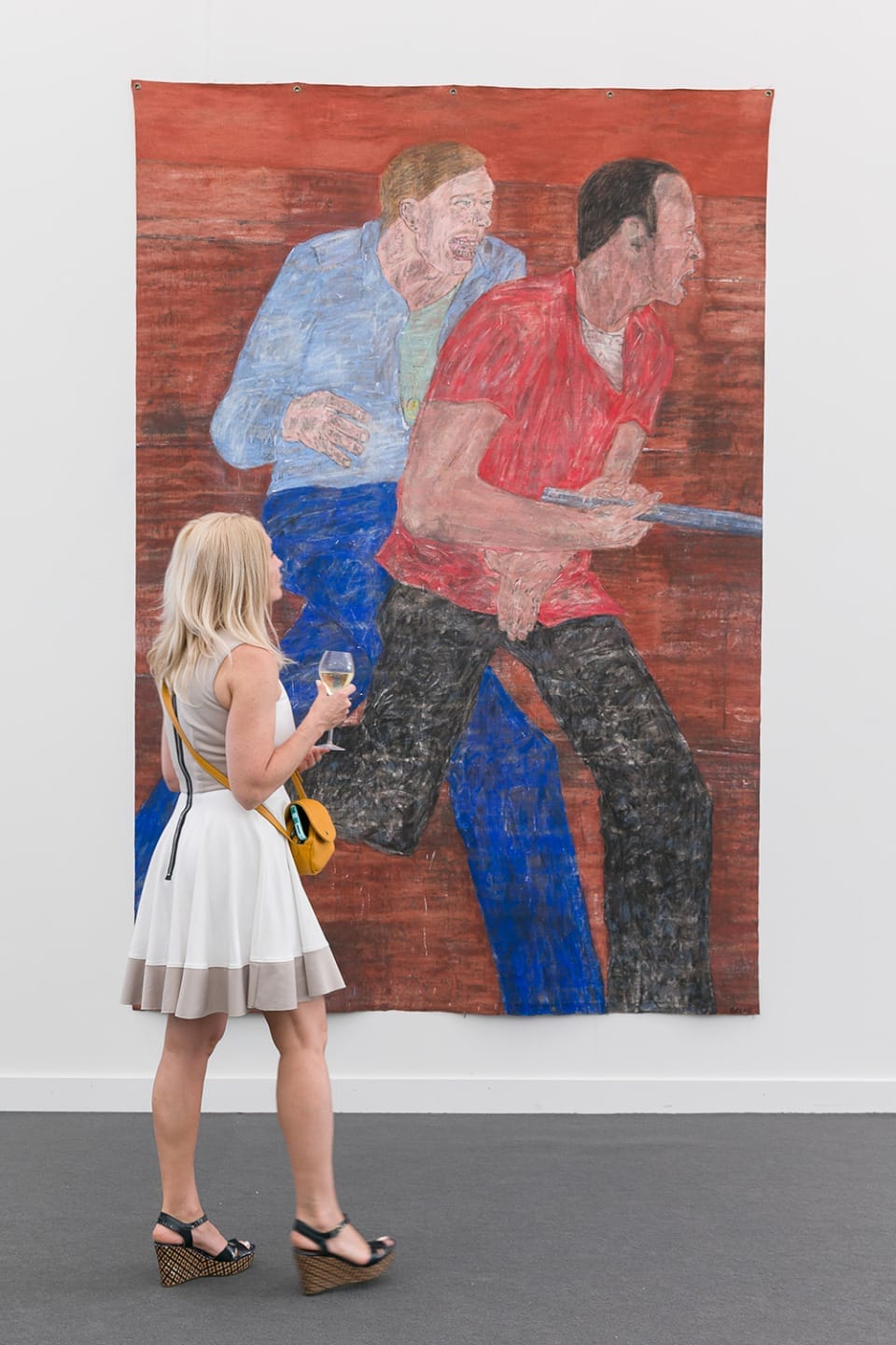 Person viewing large painting of two figures in a gallery setting, holding a glass and wearing a summer dress and sandals.