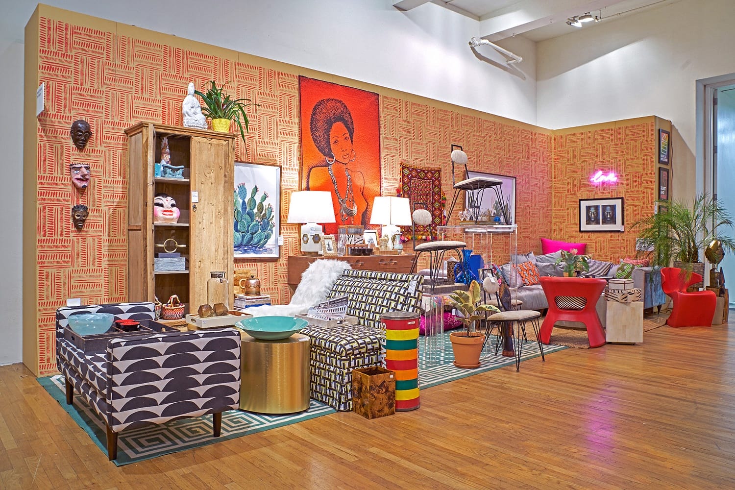 Colorful eclectic living room with patterned furniture, bright artwork, plants, and diverse decorative items displayed.