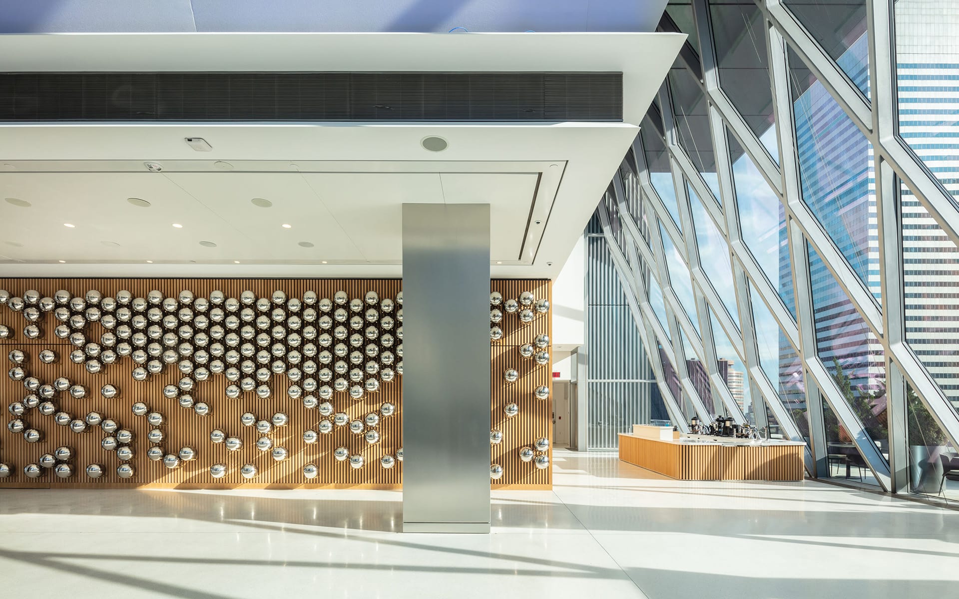 Modern lobby with a geometric wall design and large windows allowing natural light to illuminate the space