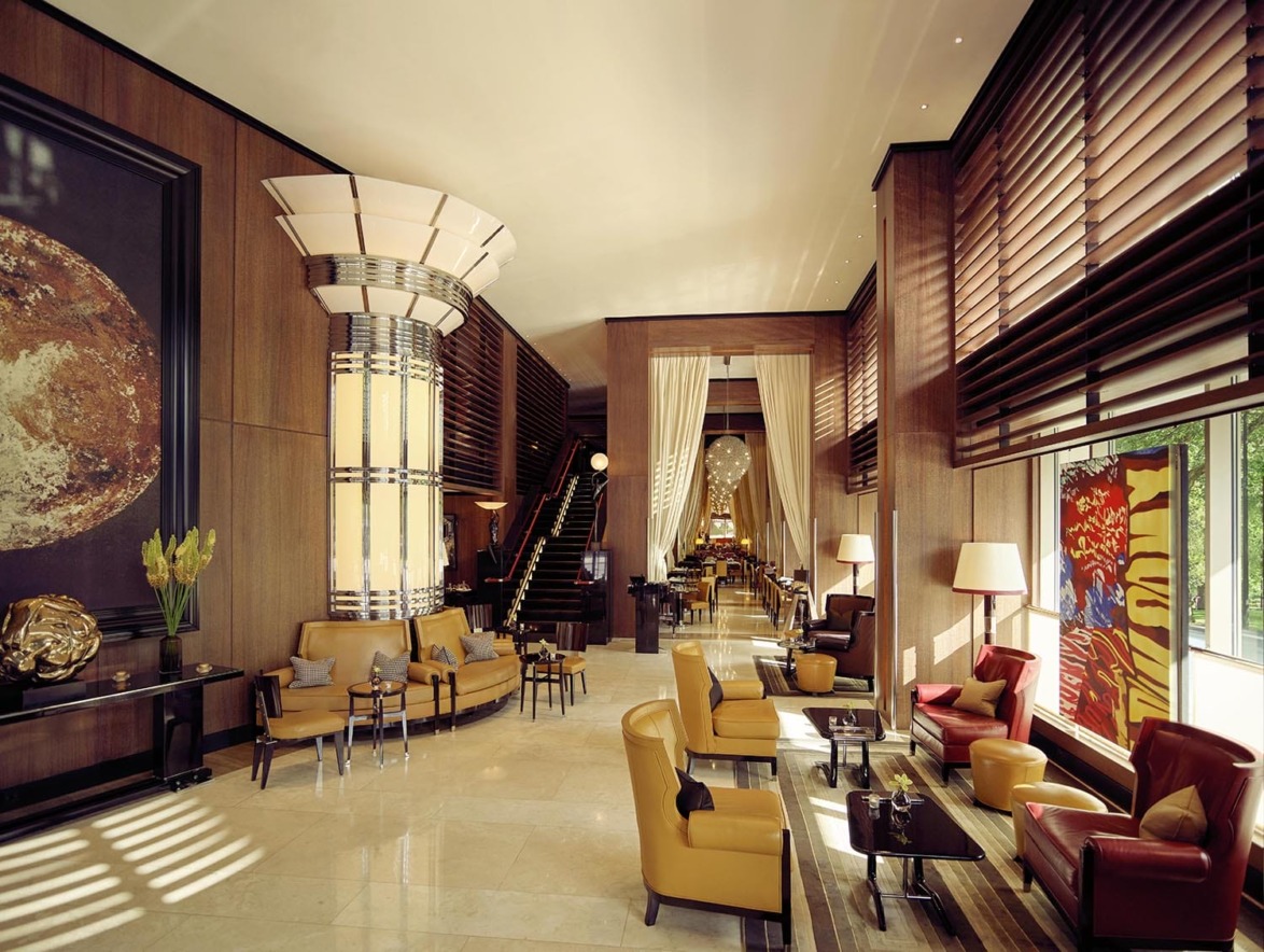 Luxurious hotel lobby with elegant furnishings, large artwork, and modern lighting. Cozy seating area with floor-to-ceiling windows.