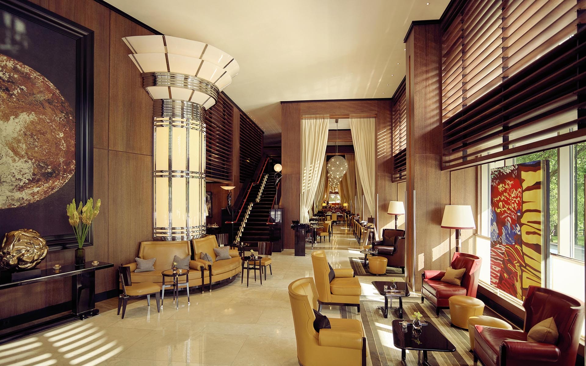 Luxurious hotel lobby with elegant furniture, large artwork, wooden accents, and soft lighting creating a warm, inviting atmosphere.