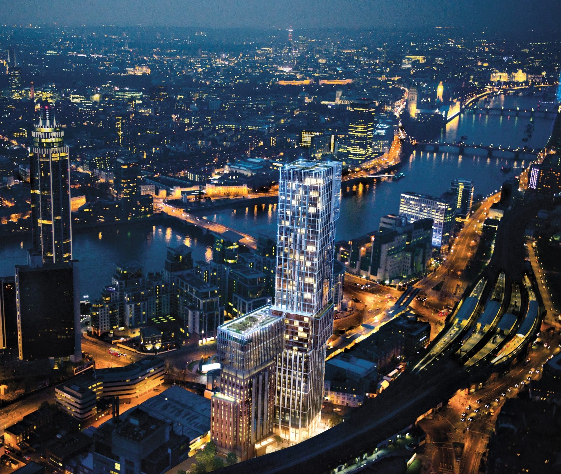 Aerial view of illuminated cityscape with skyscrapers and river at night.