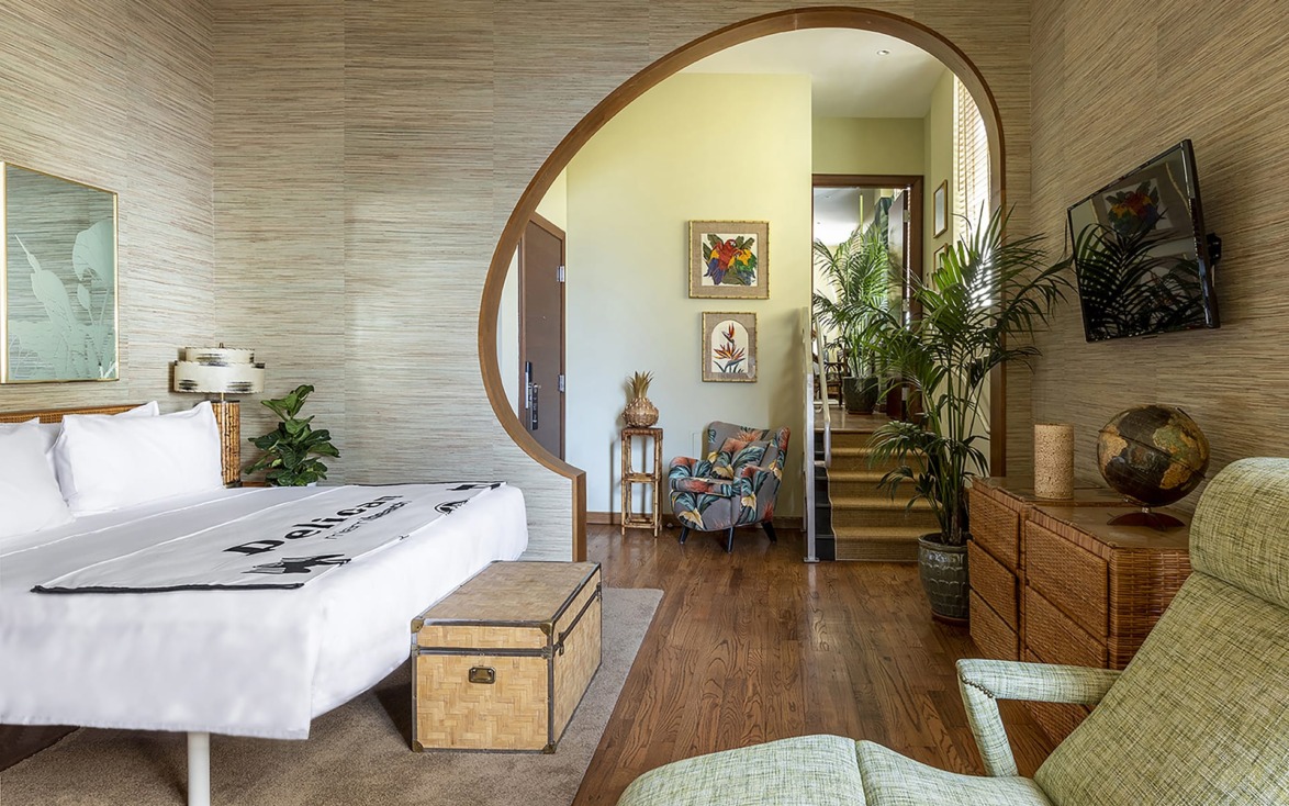 Stylish bedroom with a circular doorway, plants, and modern decor in natural tones.