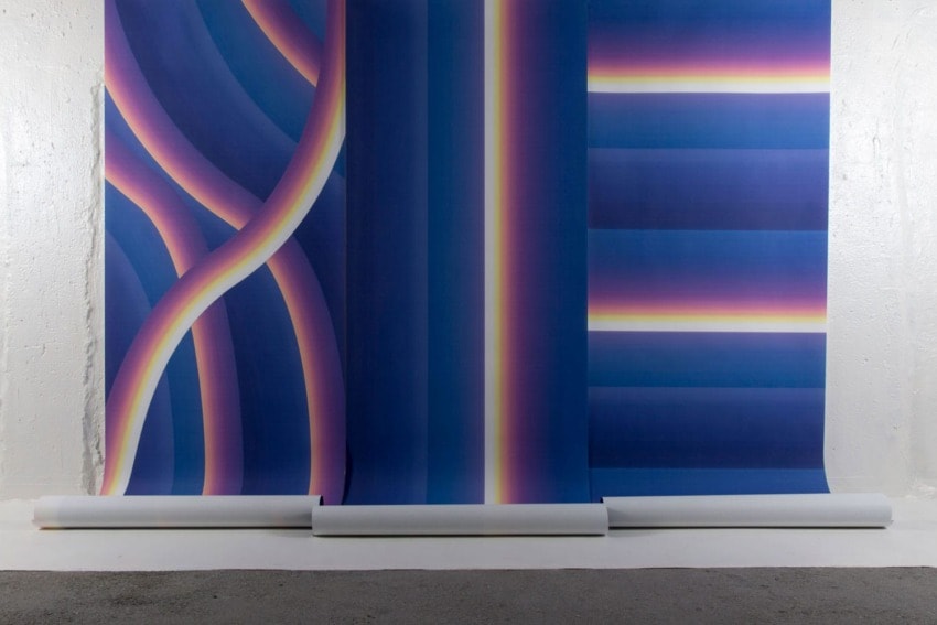 Colorful abstract art installation featuring vertical gradients and curved lines against a neutral wall background.