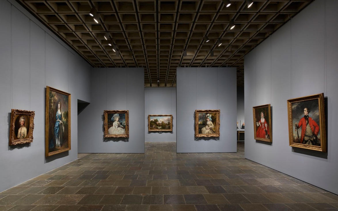 Art gallery interior with framed classical portraits on gray walls and a tiled floor.