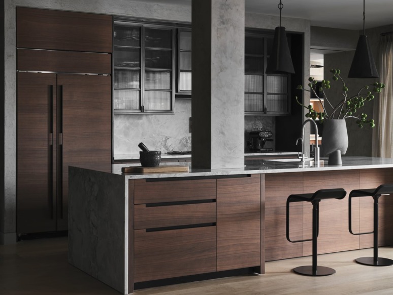 Modern kitchen with dark wood cabinets, marble countertops, black pendant lights, and sleek bar stools.