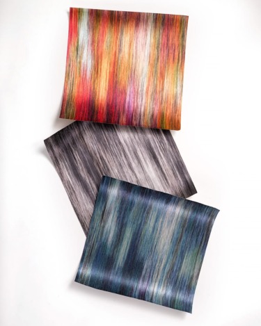 Three square sheets of colorful, textured paper overlapping each other on a white background.