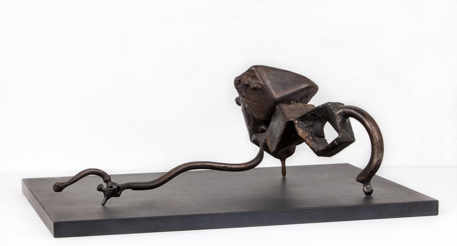 Abstract bronze sculpture with angular and curved forms resting on a black rectangular base against a plain background.