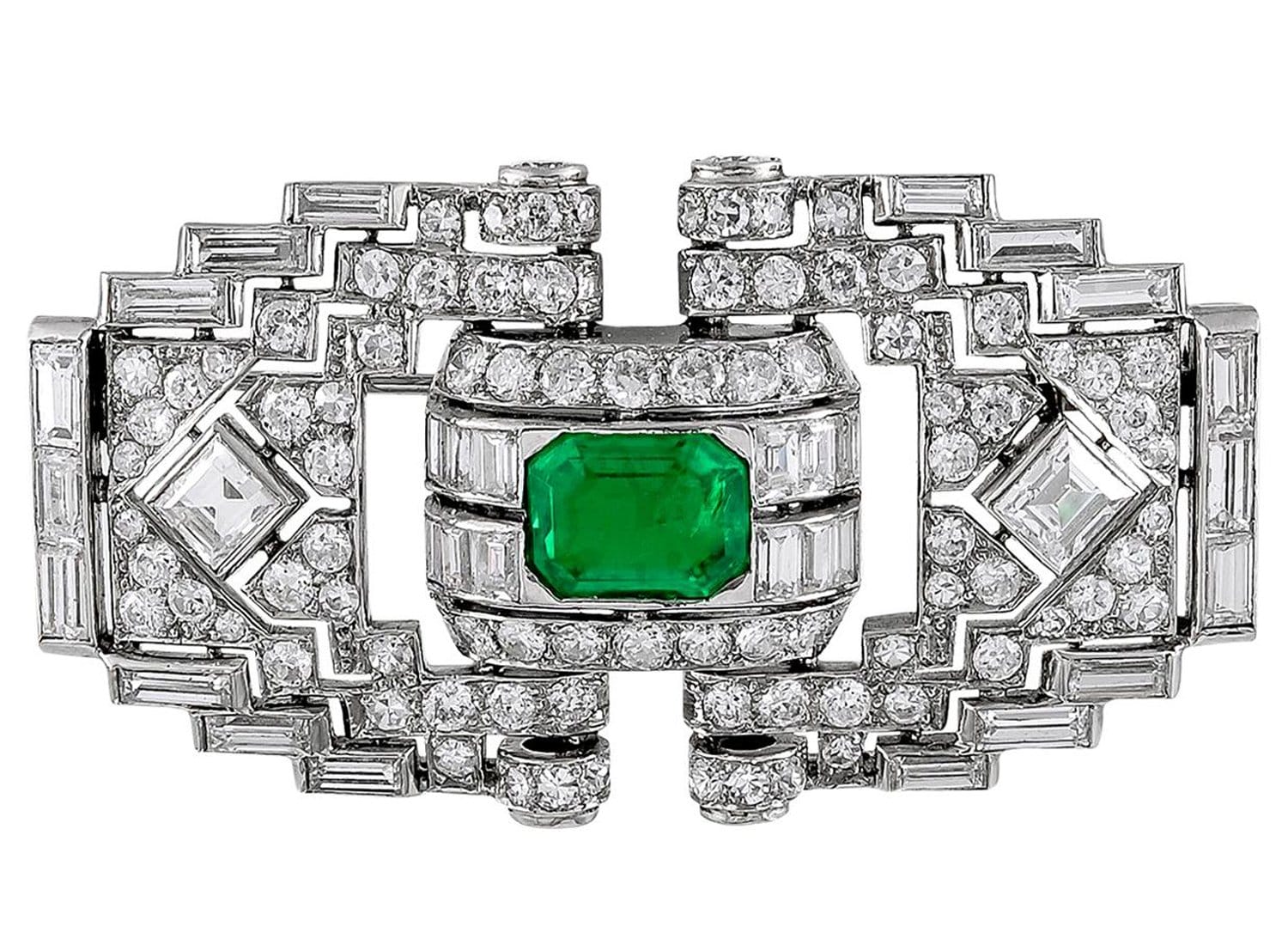 Art Deco brooch featuring diamonds and an emerald in a geometric design.