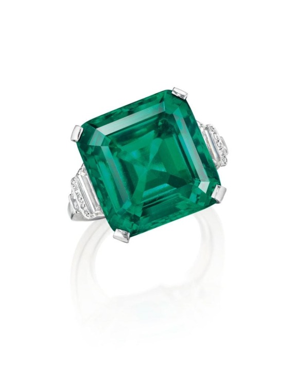 Emerald-cut green gemstone ring with silver band and diamond accents on a white background.