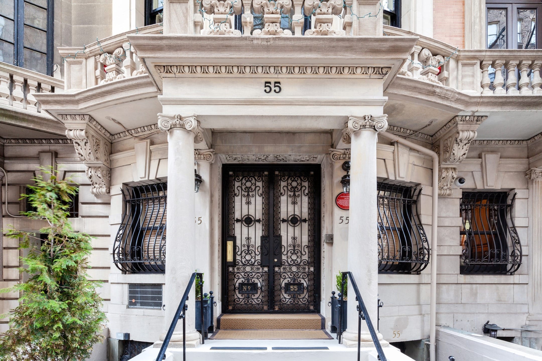 Elegant historic building entrance with ornate iron doors, tall columns, and intricate architectural details.