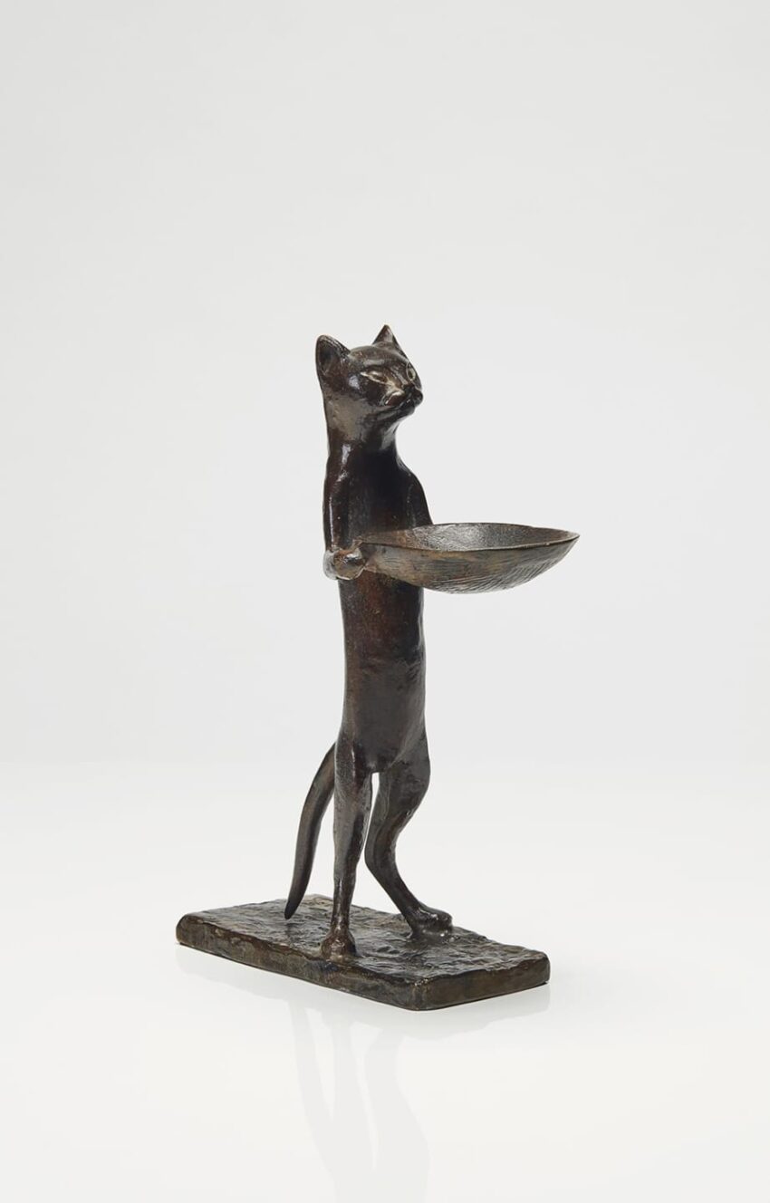 Bronze sculpture of a standing cat holding a bowl on a rectangular base against a plain background.