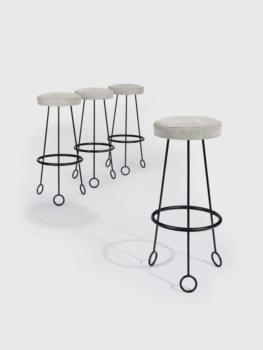 Four modern bar stools with white cushioned seats and black metal frames arranged in a diagonal line on a white background