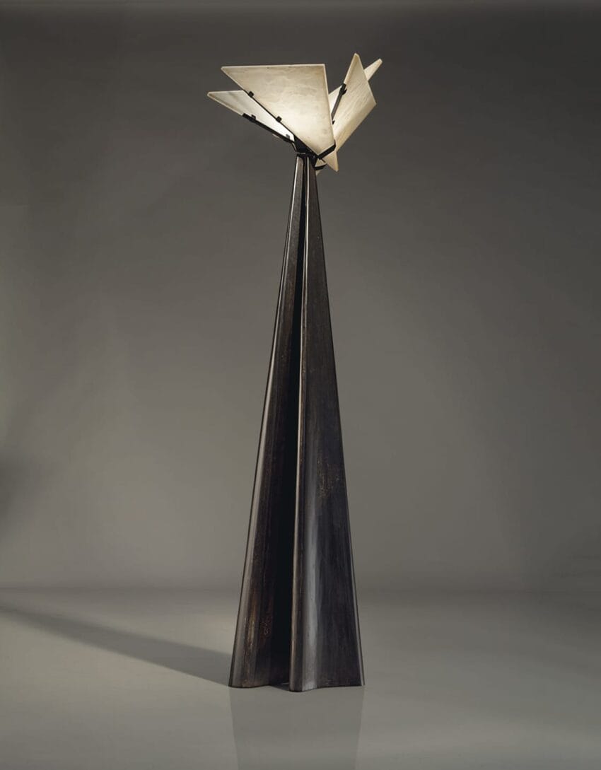 Tall abstract metal sculpture with angular, geometric design and a two-toned finish featuring dark and light sections.