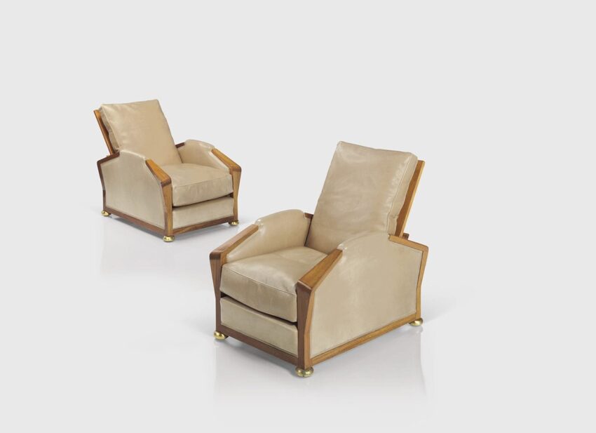 Two elegant beige armchairs with wooden frames and gold accents on a reflective white surface.