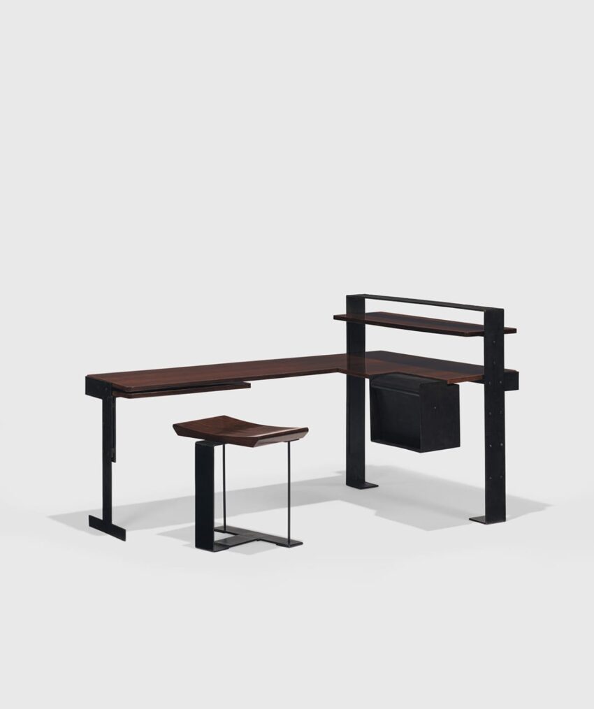 Modern minimalist desk with angular design, dark wood surfaces, black metal frame, and integrated shelf and stool.