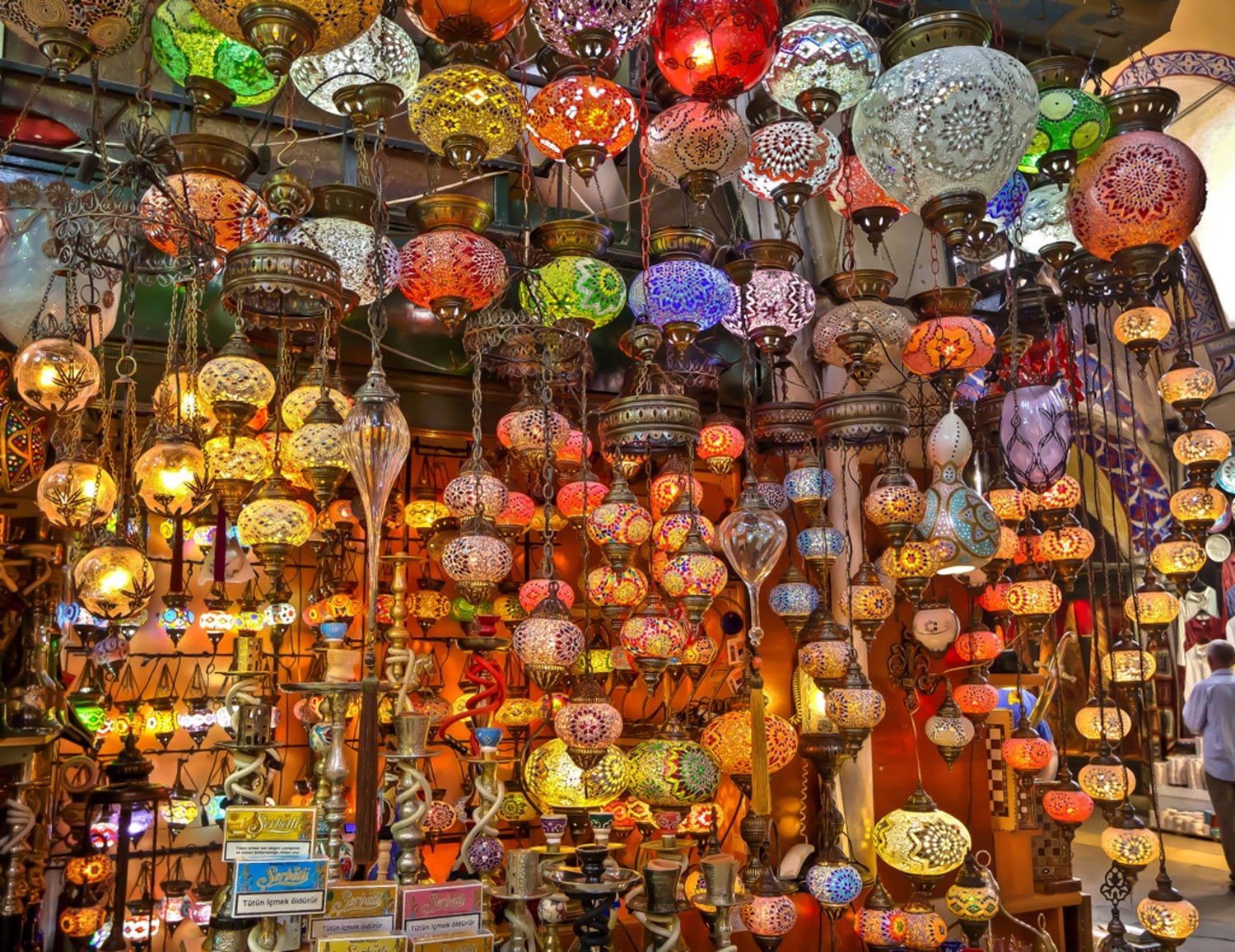 Colorful hanging mosaic lamps in a vibrant marketplace display, showcasing intricate designs and warm, ambient lighting.