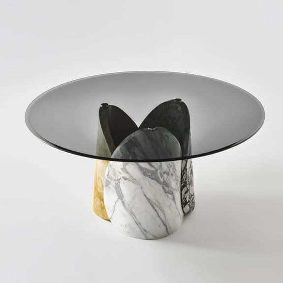 Modern round table with a smoked glass top and uniquely designed marble base in various colors.