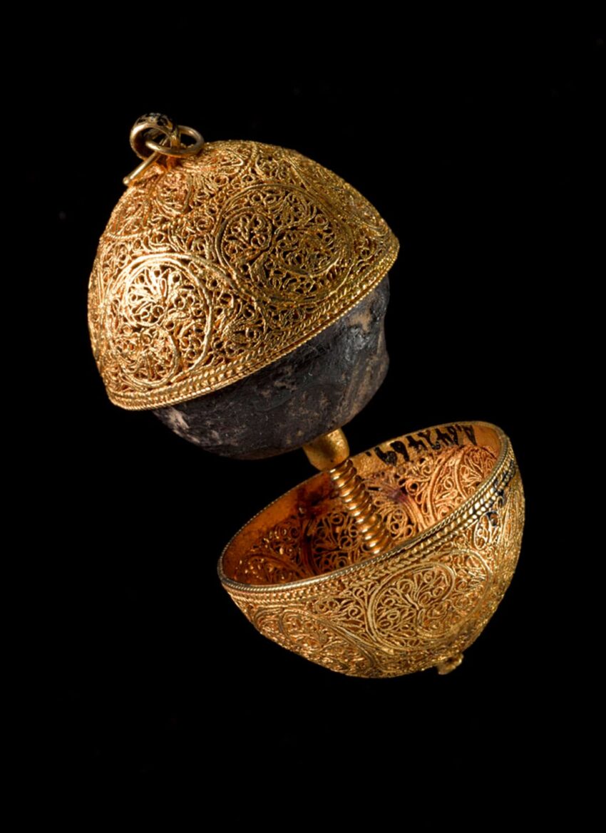Intricately designed gold filigree orb with a hinged opening, showcasing detailed craftsmanship against a black background.