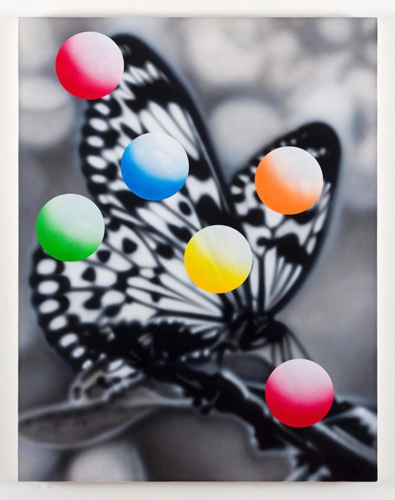 Butterfly with bold color spots overlay on wings, set against a grayscale blurred nature background.