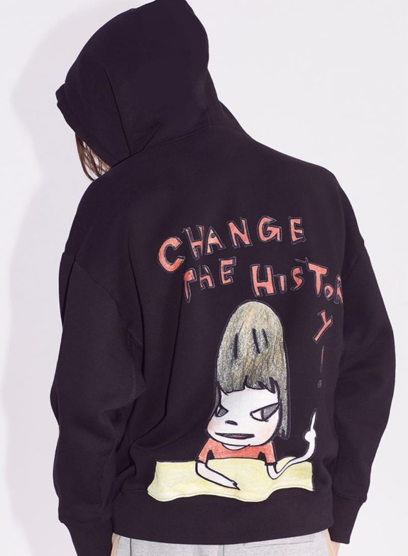 Person wearing a black hoodie with cartoon character and slogan "Change the History" on the back, standing against a white background