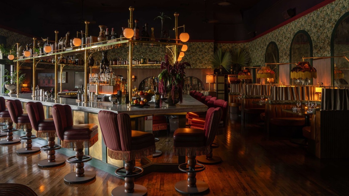 Dimly lit bar interior with elegant decor, plush seating, and ambient lighting.