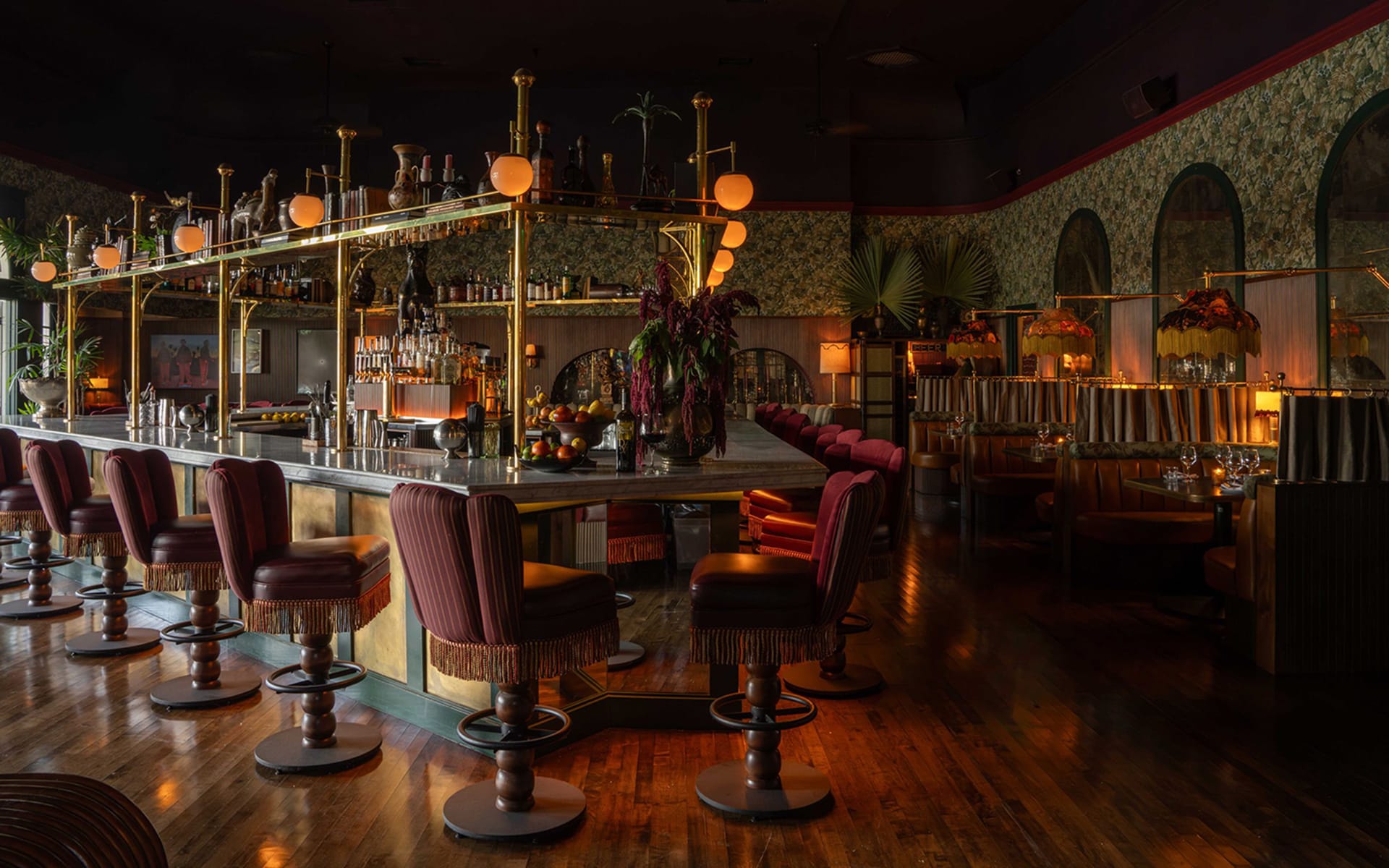 Dimly lit bar interior with elegant decor, plush seating, and ambient lighting.