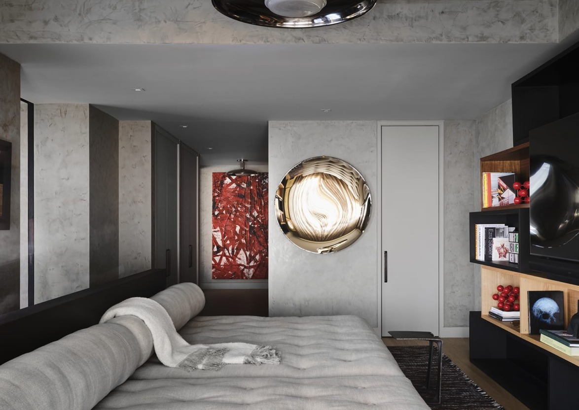 Modern living room with a large circular mirror, abstract red artwork, and bookshelves filled with books and decor.