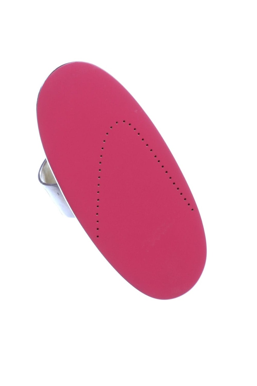 Red oval shaped iron soleplate with perforations viewed from an angle against a white background.