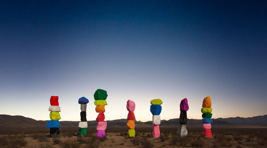 Colorful rock formations standing in a desert landscape under a darkening sky at sunset.