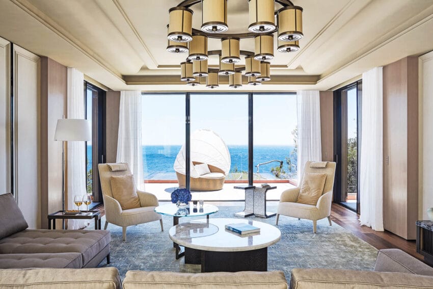 Luxury living room with ocean view, modern furniture, large windows, contemporary lighting, and elegant decor.