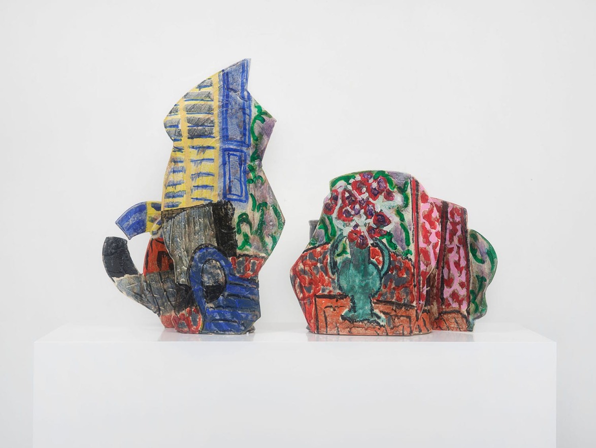 Colorful abstract ceramic sculptures with floral and striped patterns displayed on a white pedestal against a plain background.