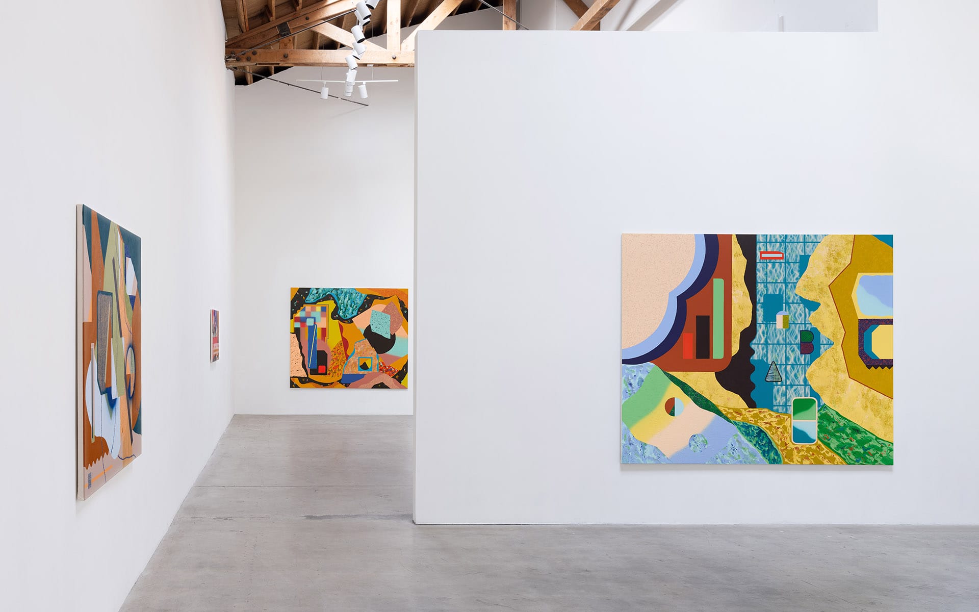 Art gallery interior with abstract paintings on white walls, featuring vibrant colors and geometric shapes.