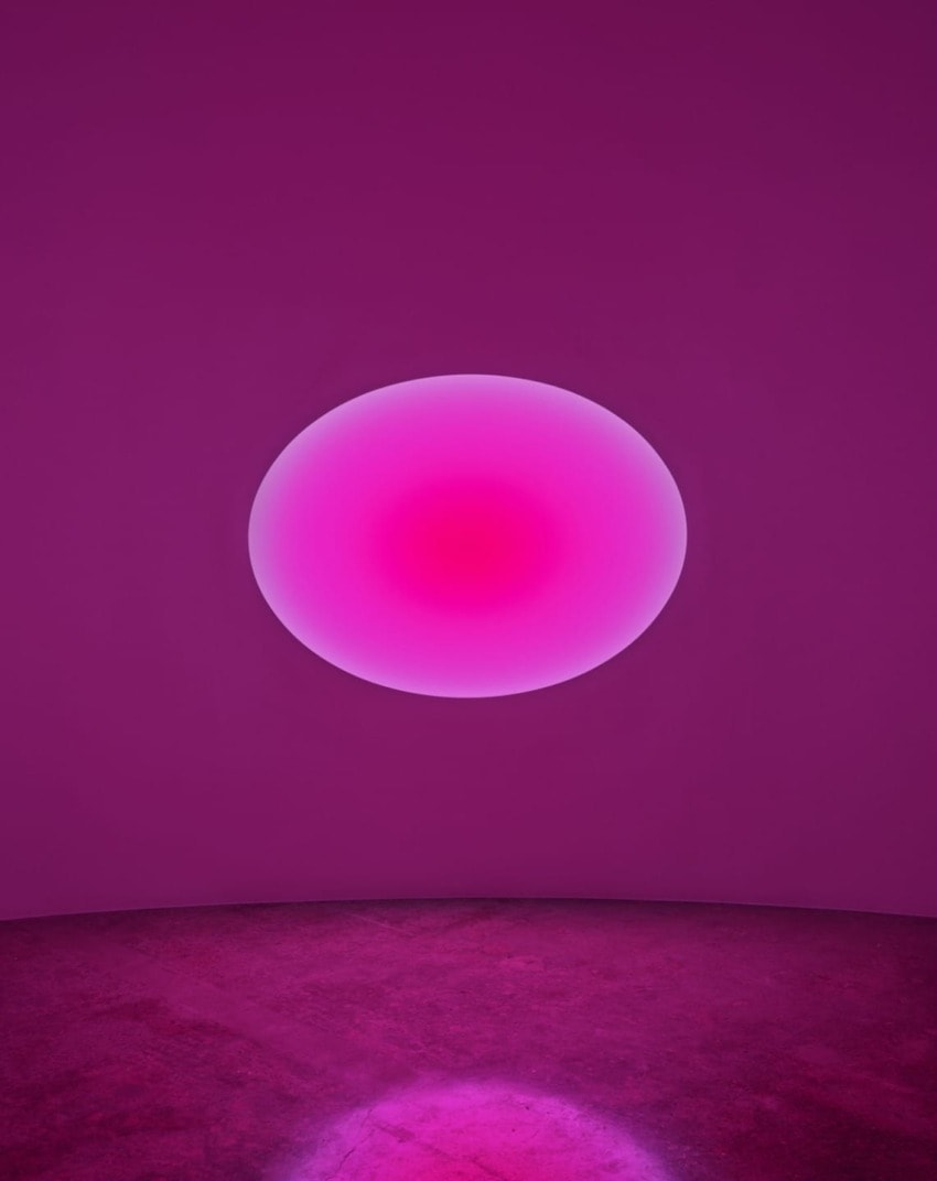 Pink and purple glowing oval on a textured wall, casting a soft light onto the floor below.