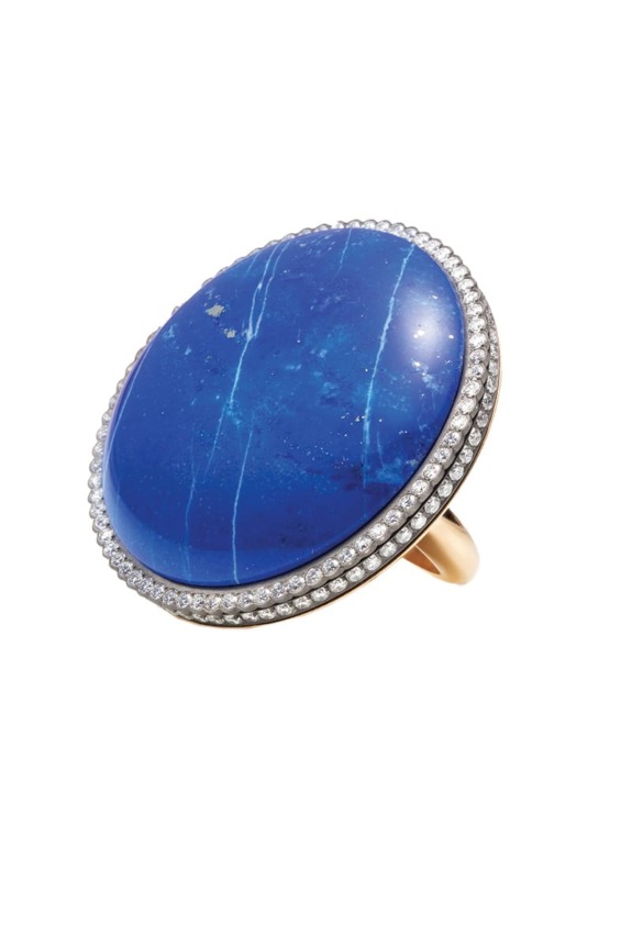 Gold ring with large blue stone surrounded by small diamonds on a white background.