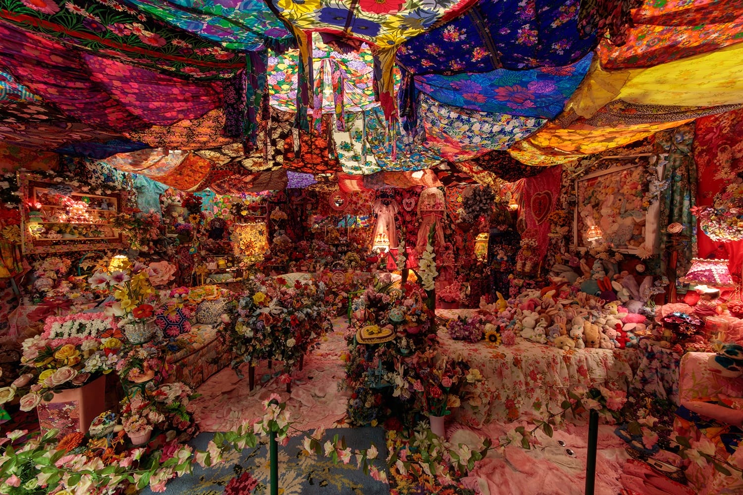Colorful room filled with floral fabric, flowers, and vivid decorations hanging from the ceiling and covering the walls.