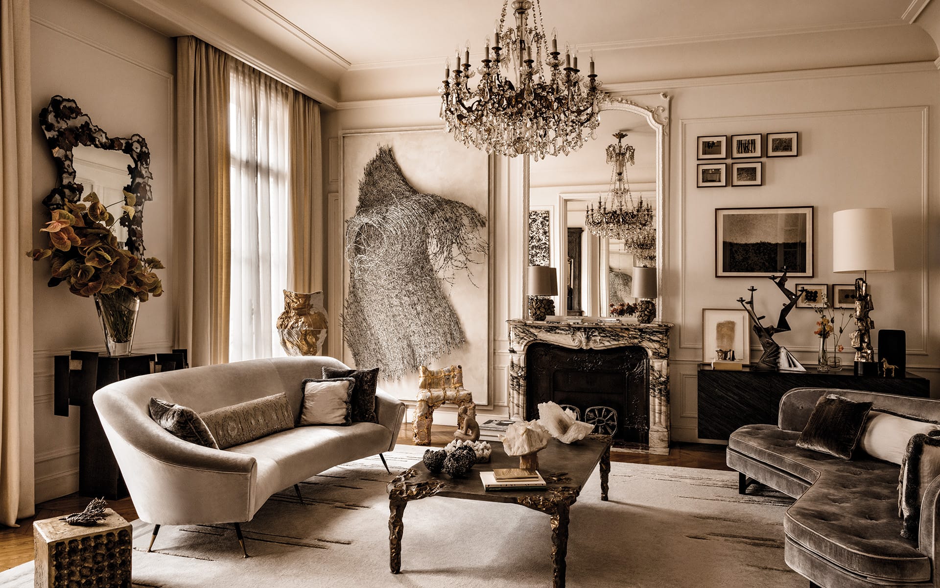 Elegant living room with classic chandeliers, ornate mirrors, and plush sofas in a neutral-toned, luxurious setting.