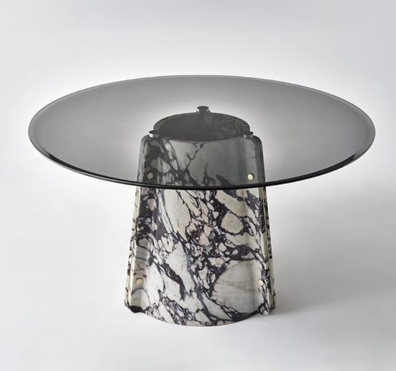 Round glass table with a marble pedestal base on a plain white background.