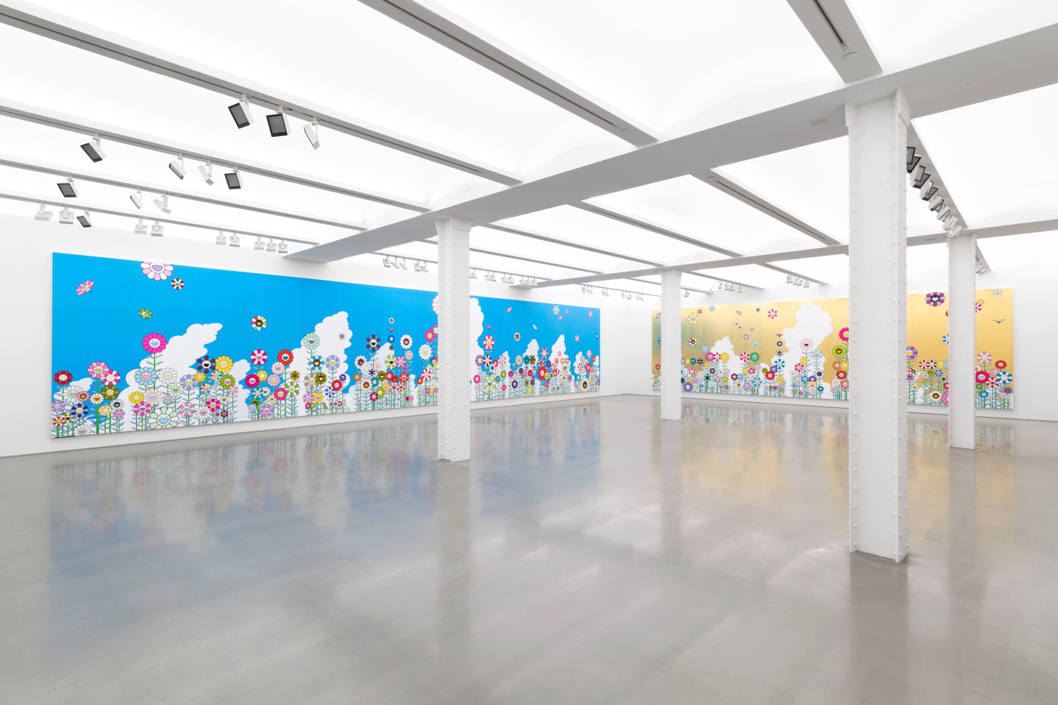 Art gallery interior with vibrant, colorful flower murals on blue and yellow backgrounds, bright lighting, and polished floors.