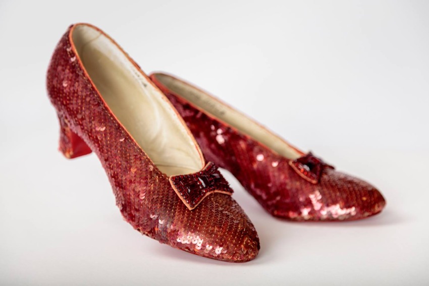 Pair of sparkling red sequin shoes with bows, placed on a white background.