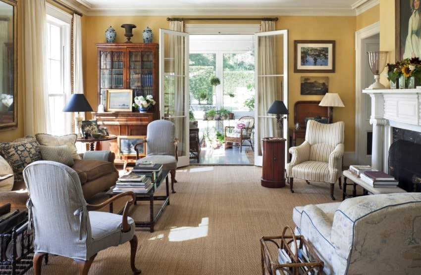 Elegant living room with vintage furniture, an open door to a garden patio, and a fireplace, creating a cozy atmosphere.