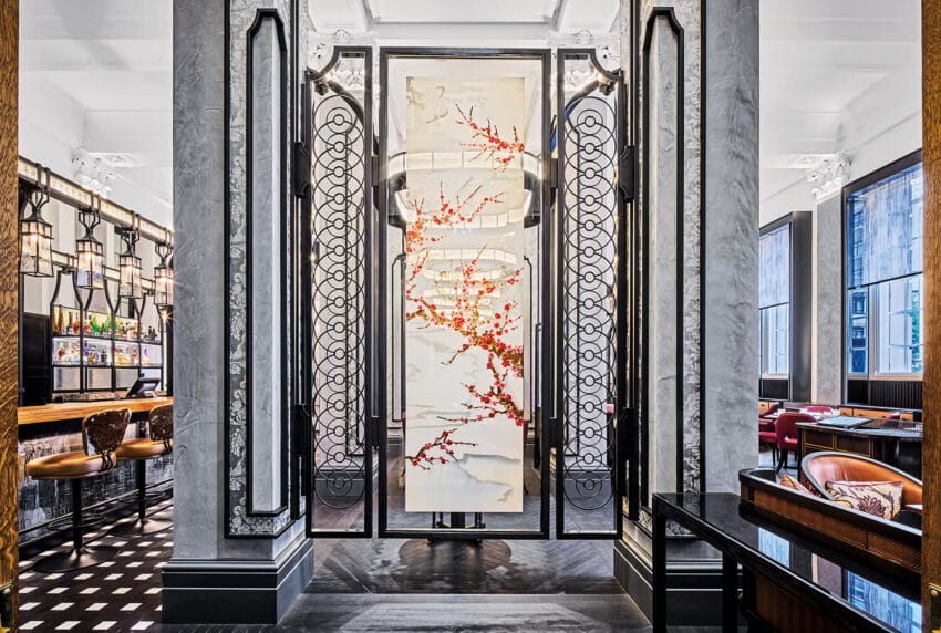 Elegant hotel lobby with intricate wall art and luxurious furnishings, featuring a prominent red floral design.