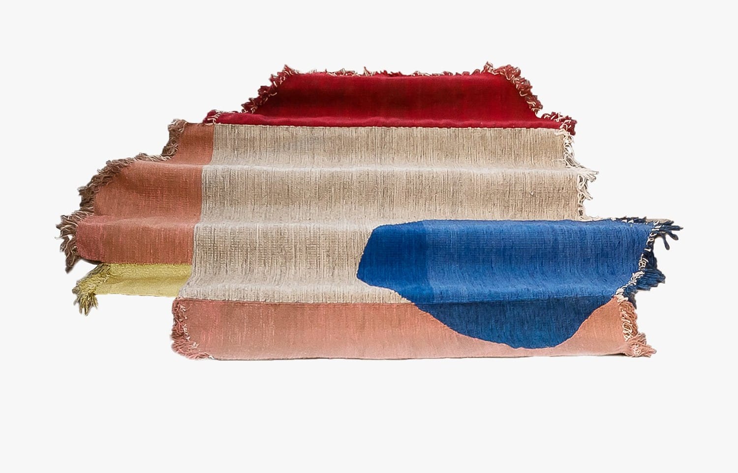 Multicolored abstract rug with fringe edges, featuring red, pink, blue, and beige sections in an artistic design.